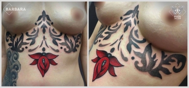 Fotografia di un busto femminile con tatuaggio in posizione pancia e sotto al seno, con decorazioni e fiore rosso in stile ornamentale e dotwork, eseguito da Barbara Schena presso il Maia Tattoo di Cornaredo Milano